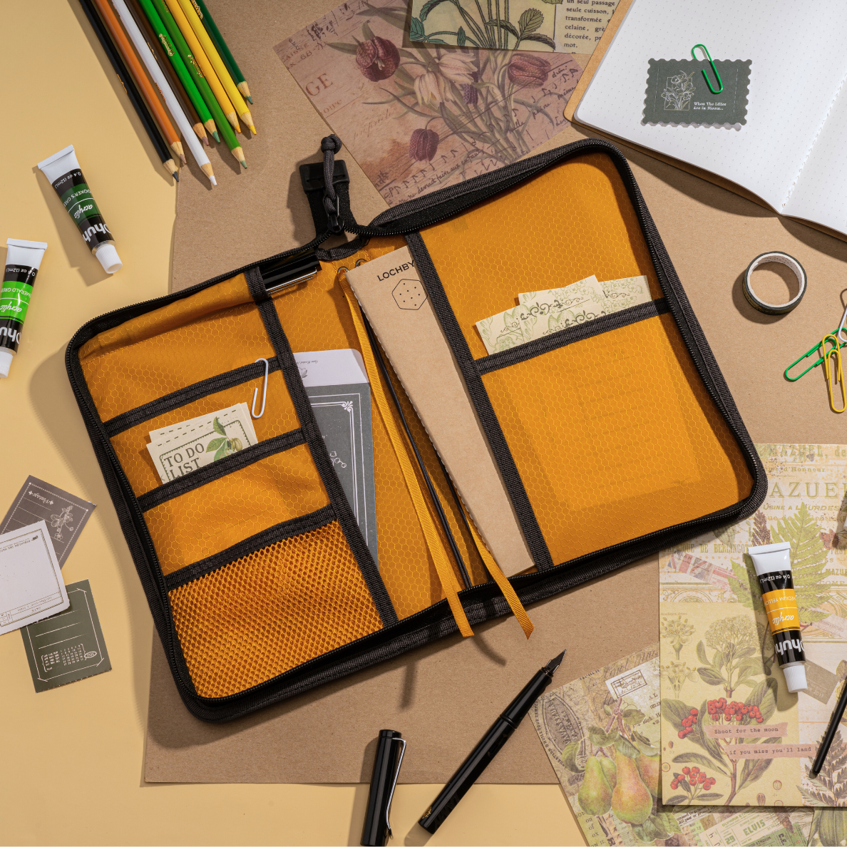 Organized desk with a LOCHBY Field Folio A5, stationery items, and a floral arrangement.