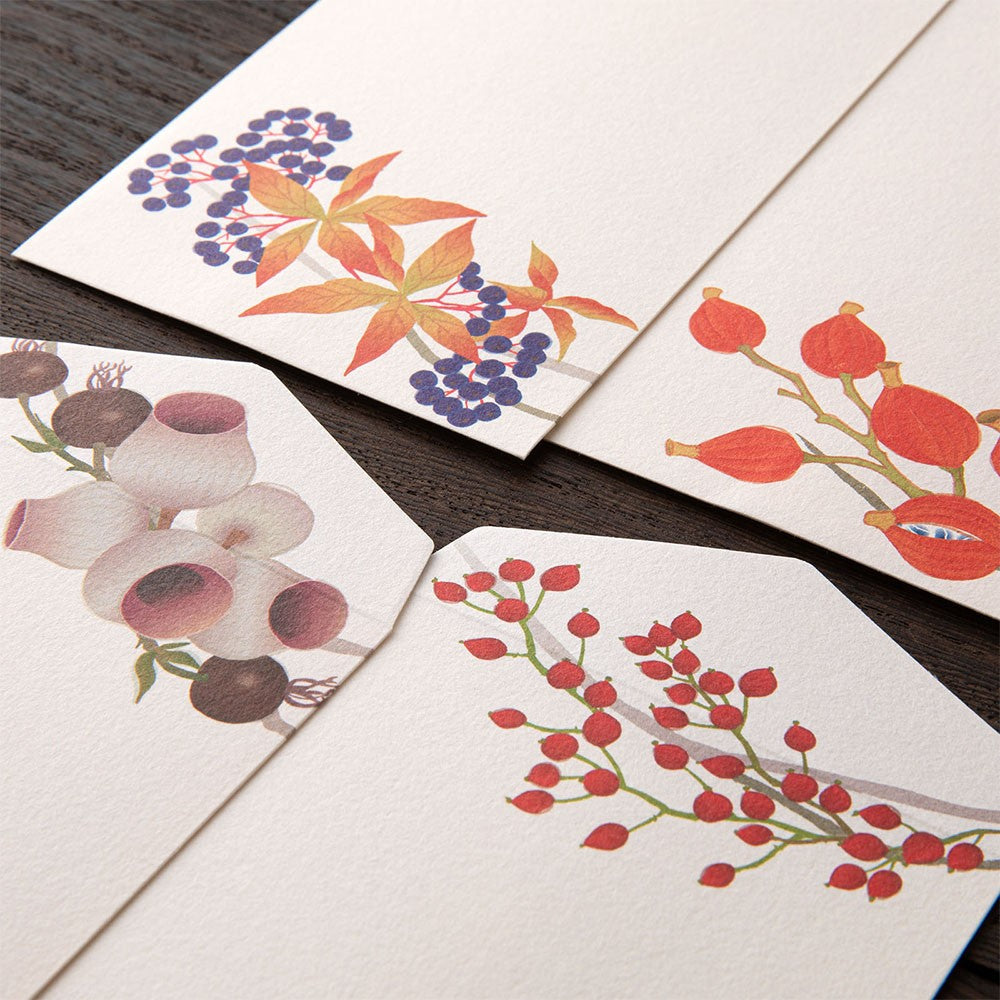 Four envelopes with floral designs on a wooden surface