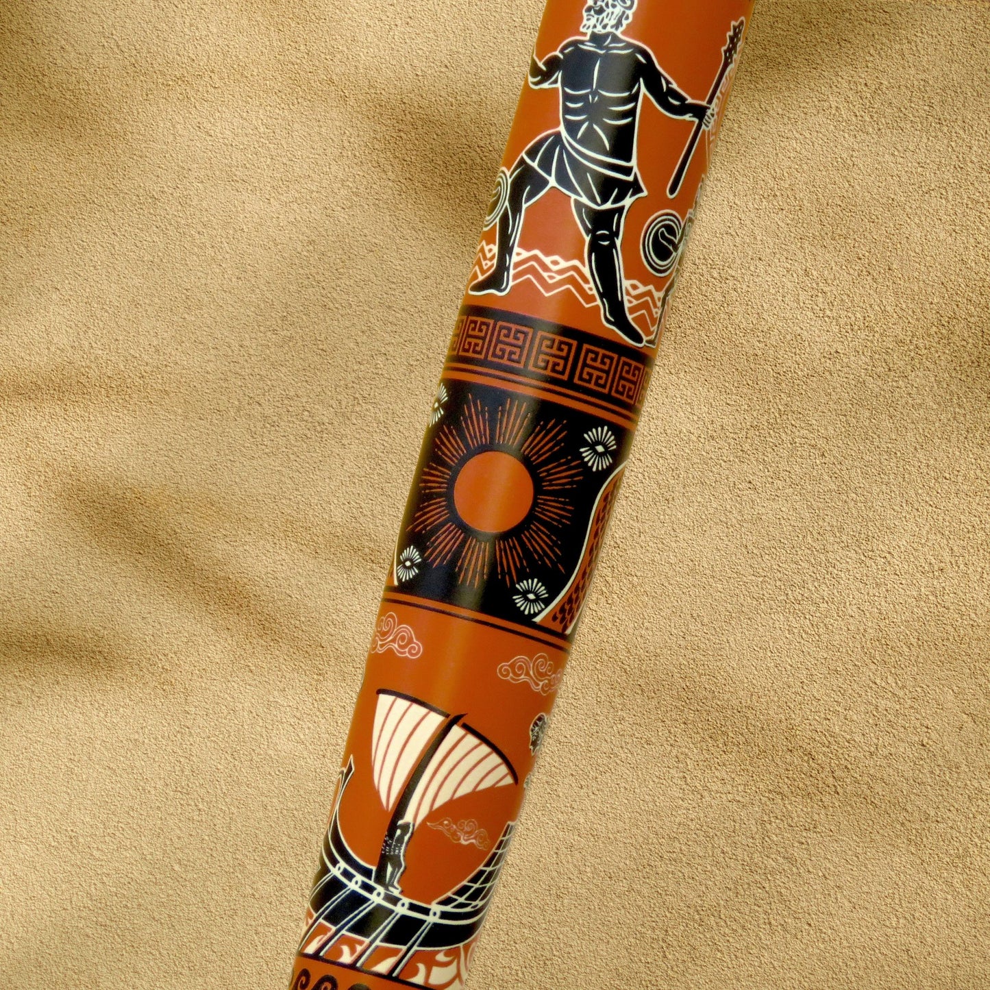 A close-up of the Odyssey orange, black, and white painted patterns, resting diagonally on a textured beige fabric background.y