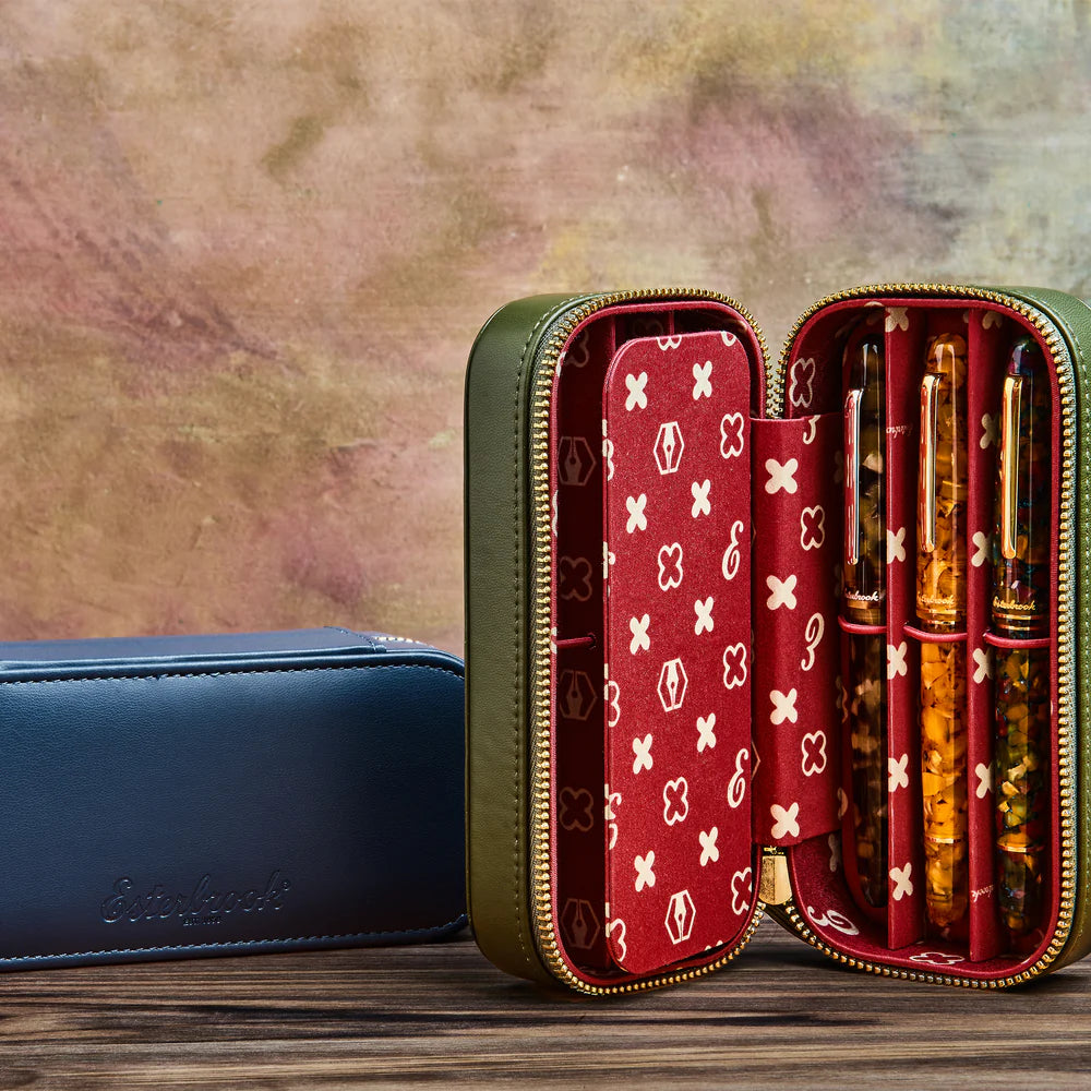 Open red and gold pen case with pens on a wooden surface and textured background