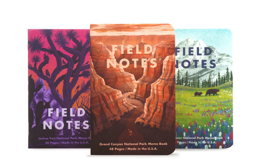 A set of three Field Notes memo books with illustrations representing Grand Canyon, Joshua Tree, and Mount Rainier national parks on the covers.