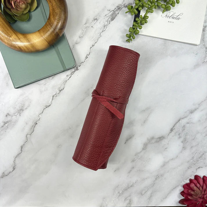 Red textured pen roll on a marble surface with decorative elements