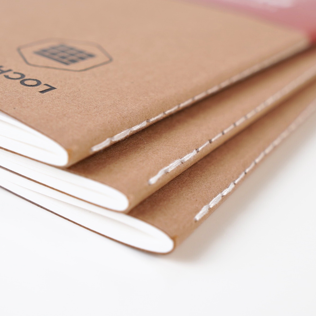 Close-up of a brown notebook with visible stitching on a white background