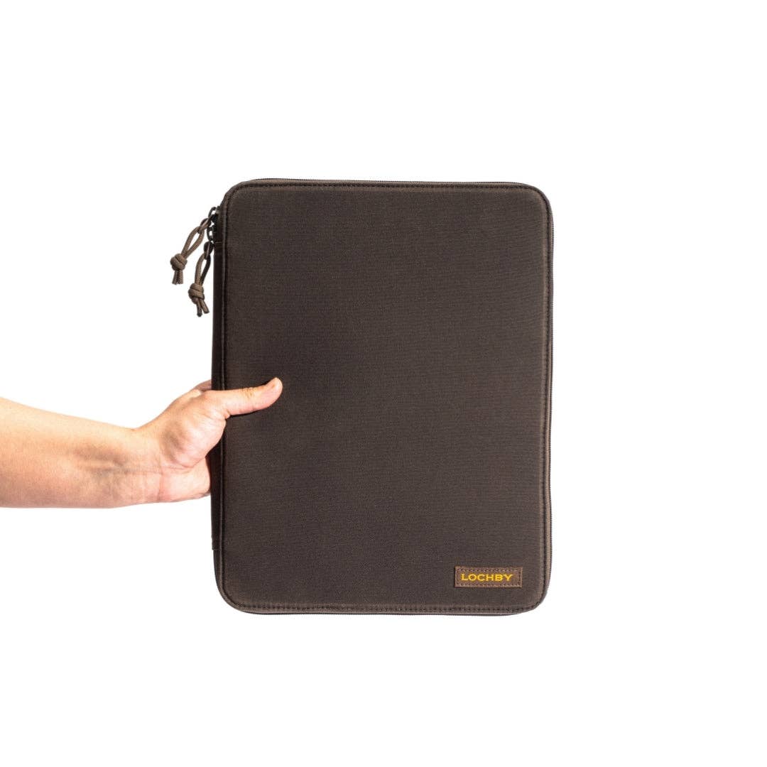 A dark brown Lochby  for a tablet or laptop, held by a person's hand against a plain white background.