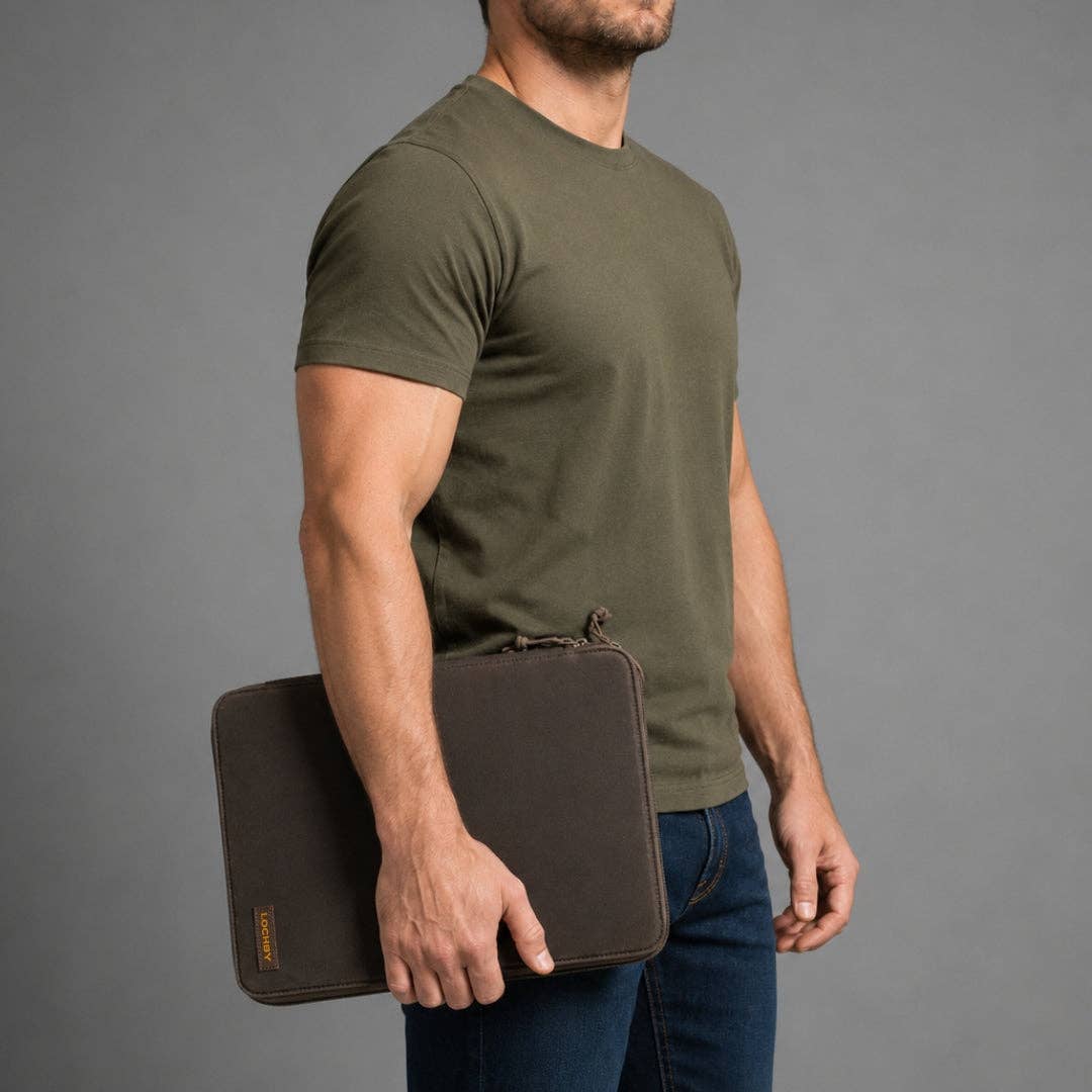 A man in an olive green t-shirt and blue jeans holds a dark brown LOCHBY Daily Folio A4 against his side, shown from the waist up against a solid gray studio background.