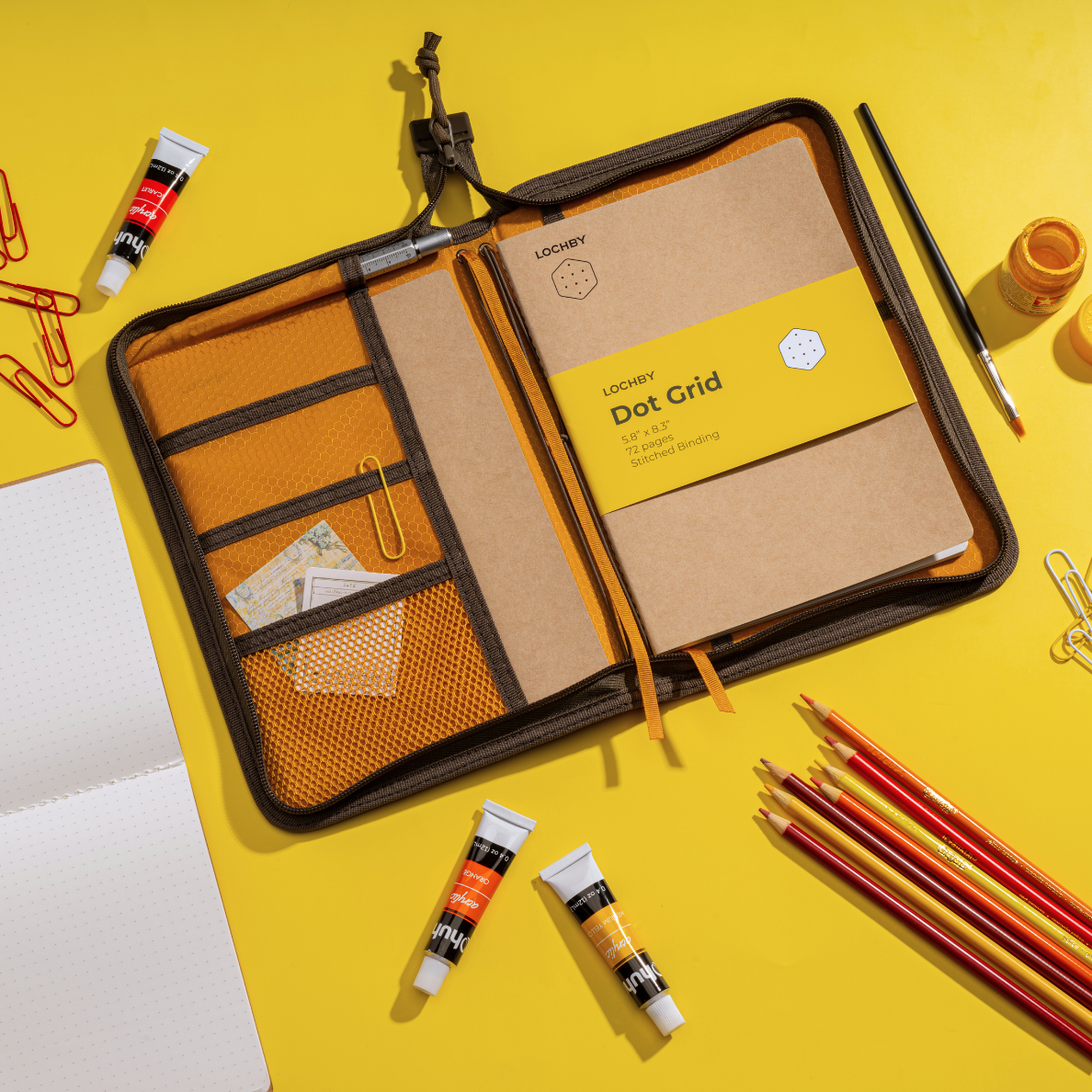Open LOCHBY Field Folio A5 with grid pages on a yellow background, surrounded by stationery items.