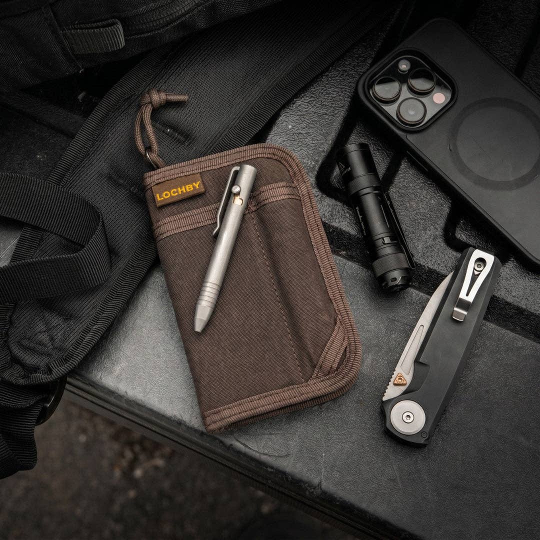 LOCHBY Mini Pocket Journal Brown with Assorted tools including a pen, knife, flashlight, and phone case on a dark surface