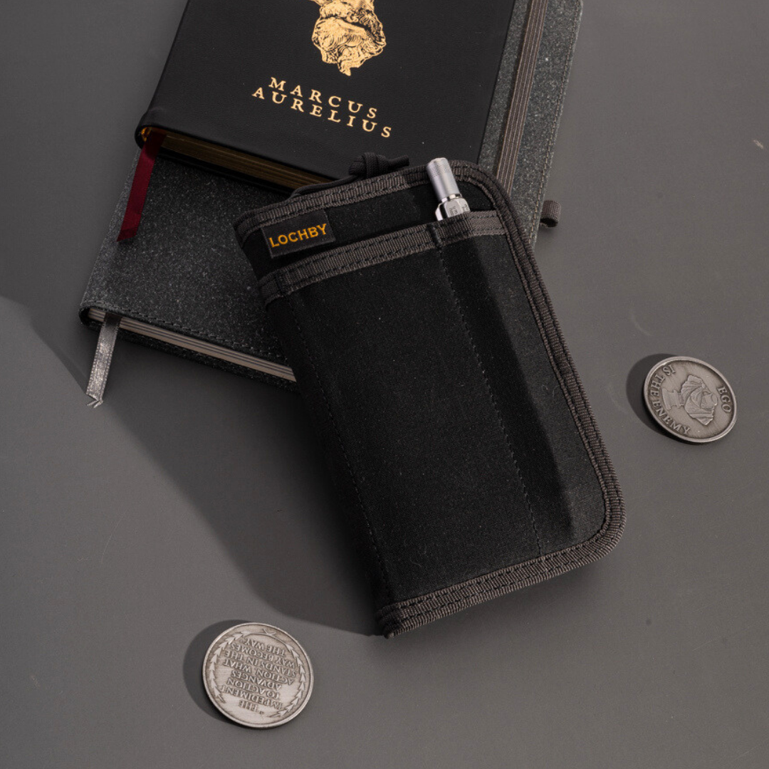 Black pouch with 'LOCHBY' branding on a gray surface with coins and a book.