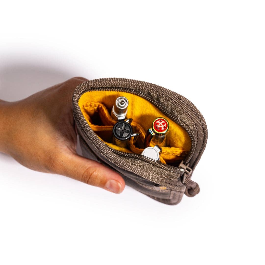 Hand holding a Quattro zippered pouch with pens on a white background