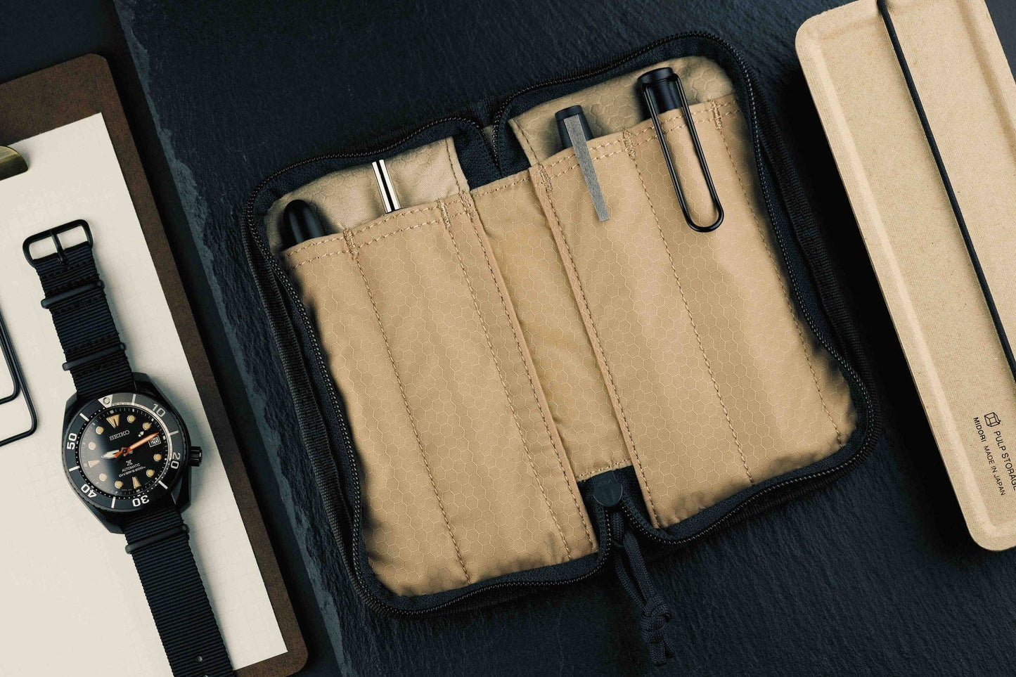 Lochby Quattro Pen Holder interior Beige fabric pouch with black zipper on a dark surface.