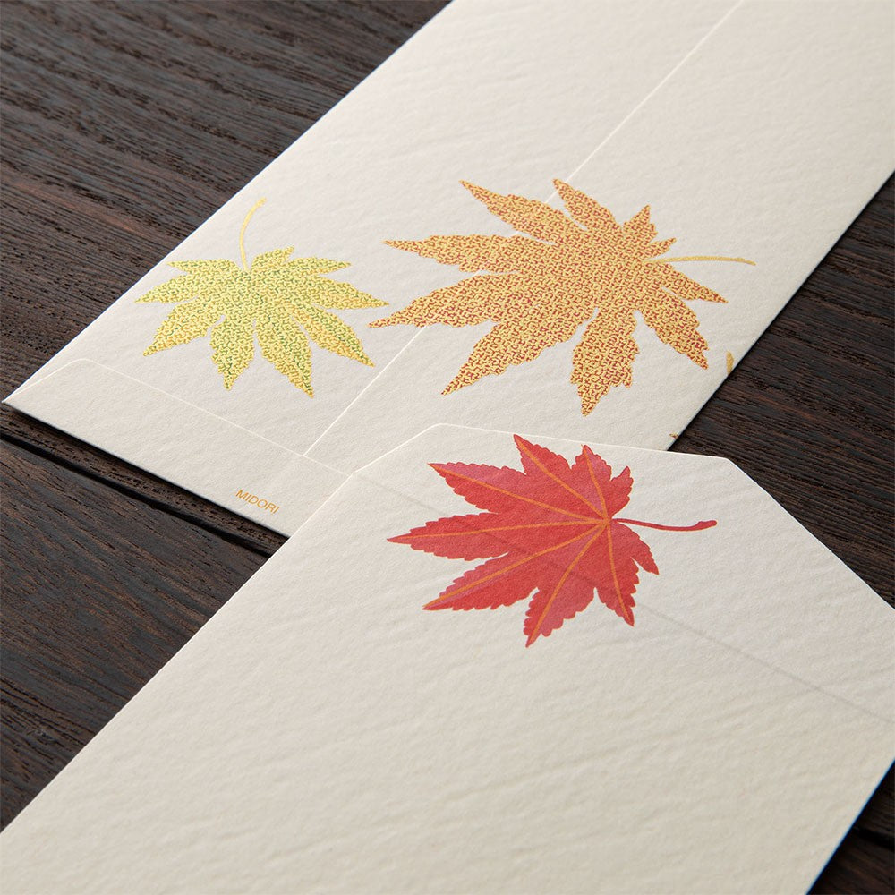 Midori Fallen Leaves S2 envelopes with autumn leaf designs on a wooden surface