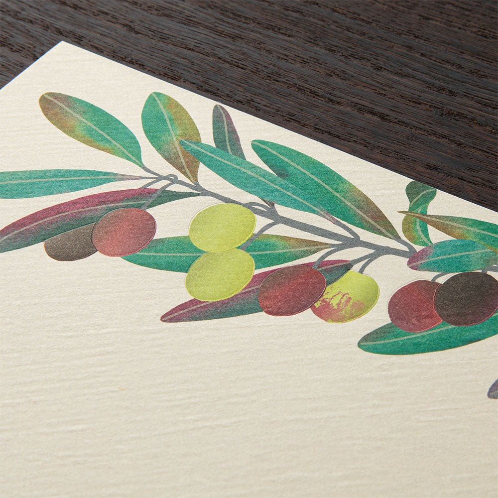 Decorative paper with an olive branch design on a wooden surface