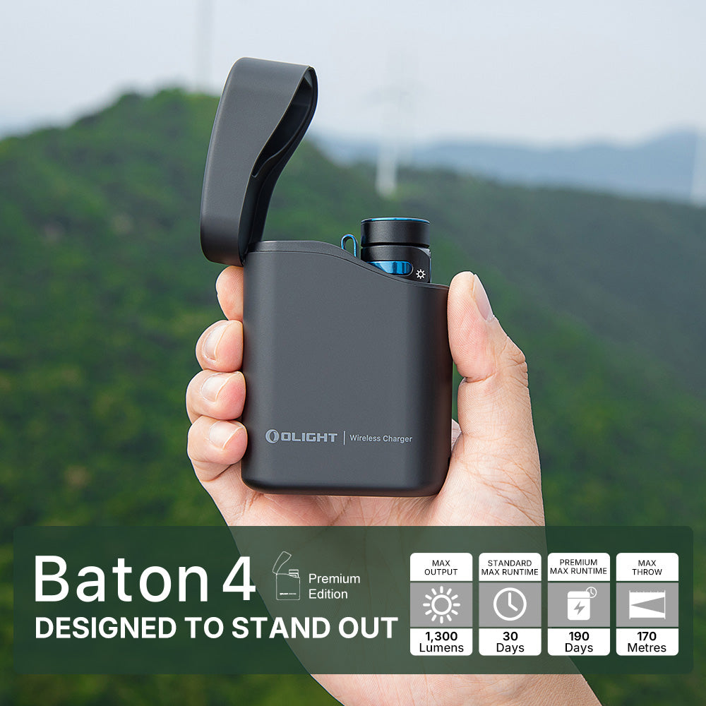 Hand holding a black Olight Baton 4 wireless charger with a mountainous background