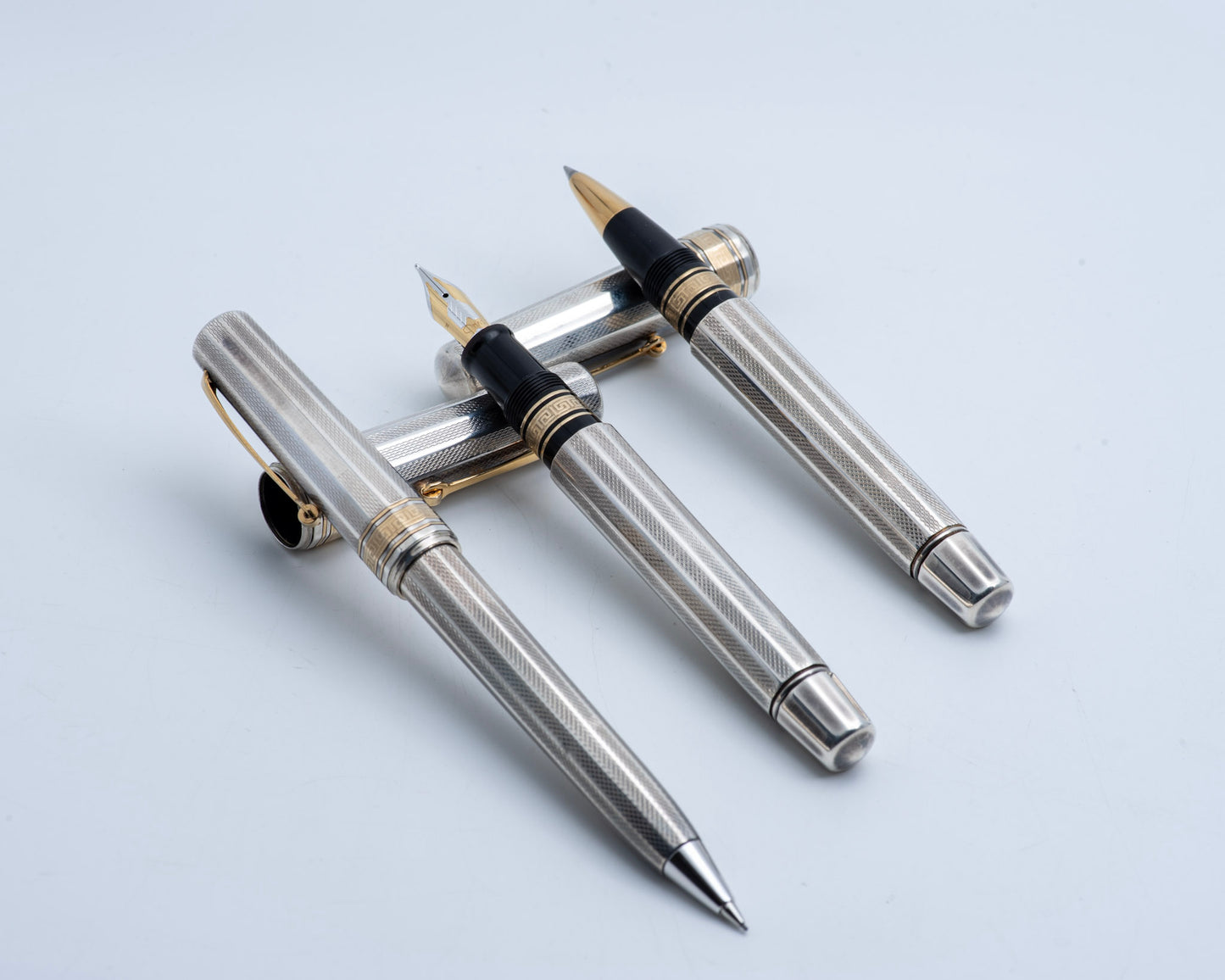 Two silver fountain pens with gold accents on a light gray background