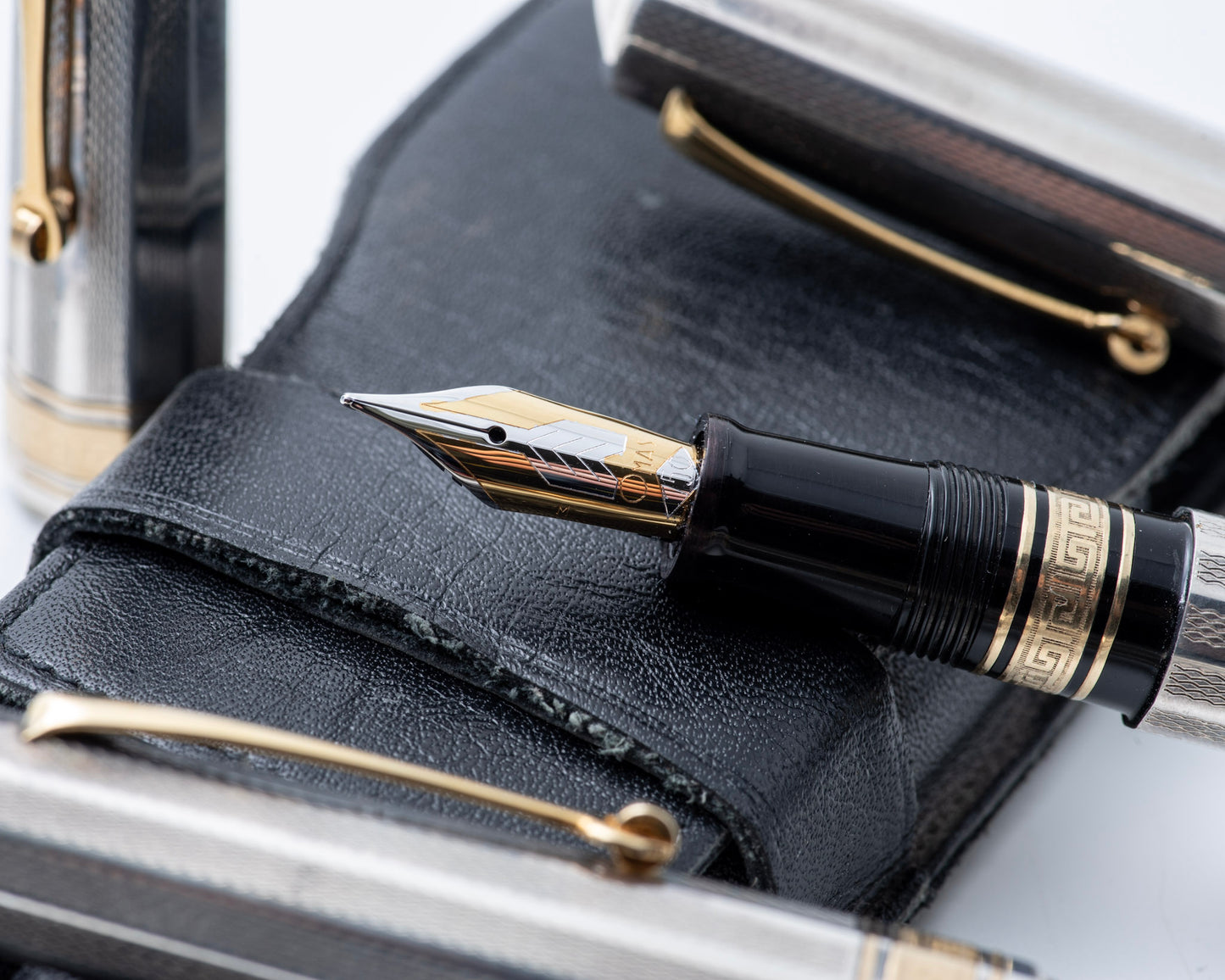 Fountain pen with gold accents on a black leather surface