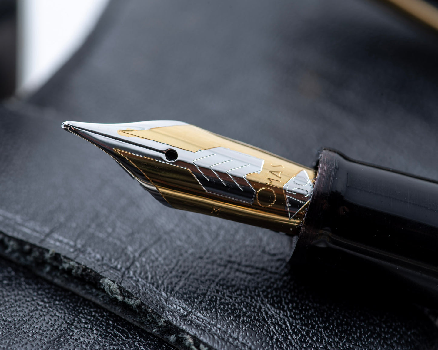 Close-up of a fountain pen nib on a textured black surface