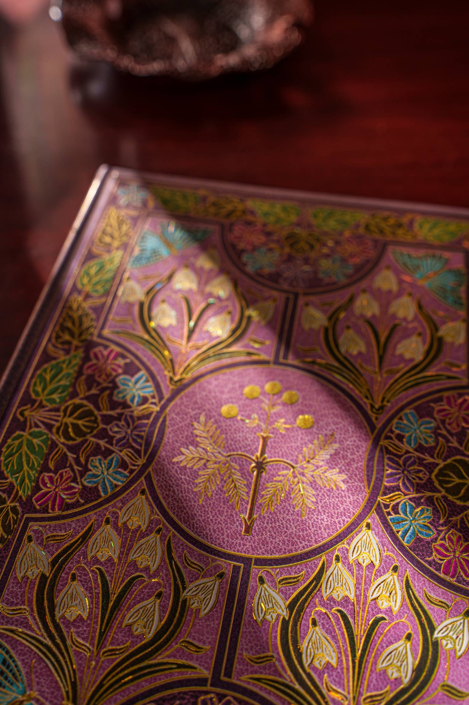 Decorative journal with floral patterns and gold accents on a wooden surface