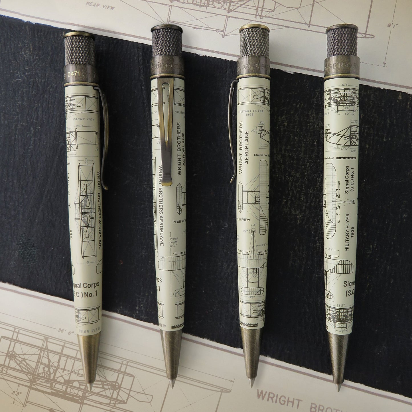 Retro 51 Wright Brothers Aeroplane - Rollerball pen showing all angles with a vintage architectural blueprint print, arranged vertically on a dark textured background with blueprint sheets visible.