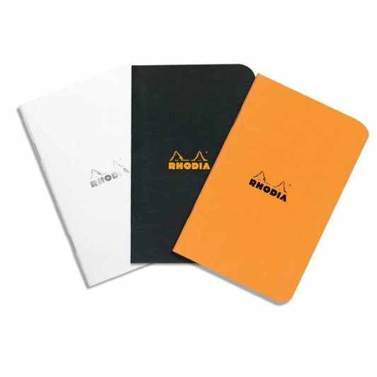 Three Rhodia Classic A4 notebooks in white, black, and orange on a white background